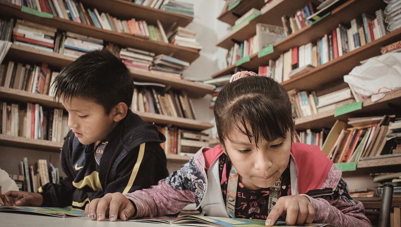 Una niña y un niño leyendo en una biblioteca. Imagen cedida por La Poderosa, integrante de IED.