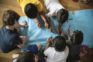 Cenital de niños dibujando. Captura de imagen de la nota.