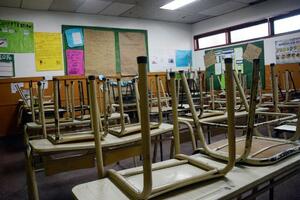 Aula vacía con sillas apoyadas sobre los pupitres.
