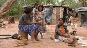 Mujeres y niños con el rostro pixelado en un paraje rural del Chaco salteño, junto a viviendas precarias, imagen de la nota "Infancia en deuda | Organizaciones advierten sobre la situación alimentaria de niños y adolescentes del chaco salteño".