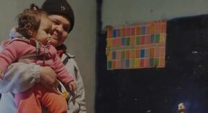 Mujer con niña en brazos, recorte de imagen de la nota "Infancia pobre: tres de cada 10 chicos viven hacinados y muchos comparten la cama".